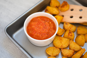 Bowl with spicy tomato salsa or mojo rojo, a red hot sauce made of roasted bell peppers, paprika, chili, onions and garlic served with patatas bravas, a traditional Spanish baked potatoes tapas dish