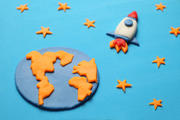 Creative craft plasticine rocket in open space, astronaut dreams. Stars, planet earth. Cartoon art.