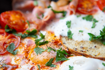 Fried eggs with bacon, toast and tomatoes in a pan
