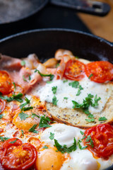 Fried eggs with bacon, toast and tomatoes in a pan