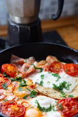 Fried eggs with bacon, toast and tomatoes in a pan