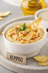 Homemade hummus bowl with chips, chickpeas, parsley and paprika