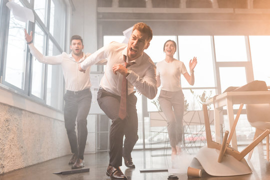 businesspeople running and screaming in office with smoke