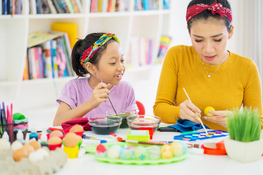 Asian woman and her child decorate eggs with dye