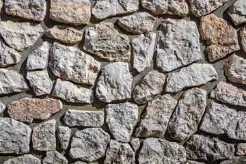 Wall made of cement and irregularly shaped stones. Architectural detail, closeup. Texture, material background.