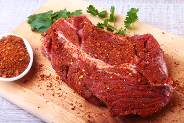 Raw beef steak with spices Leaves of coriander on wooden cutting board. Ready for cooking.