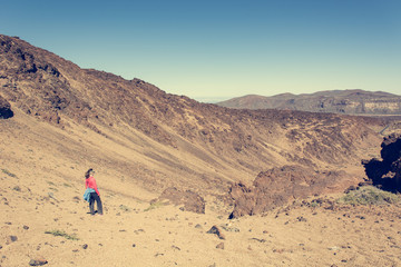 Sporty woman running down volcanic slope lifting dust trail.