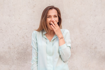 Young woman standing isolated on wall looking aside laughing cheerful