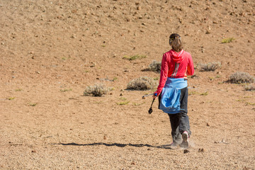 Sporty female hiking desert wasteland across volcanic crater.