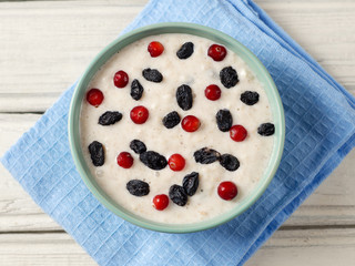 oatmeal with raisins and cranberries on a wooden table. wholesome breakfast