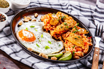 Grilled chicken meat with groats and fried egg on wooden table