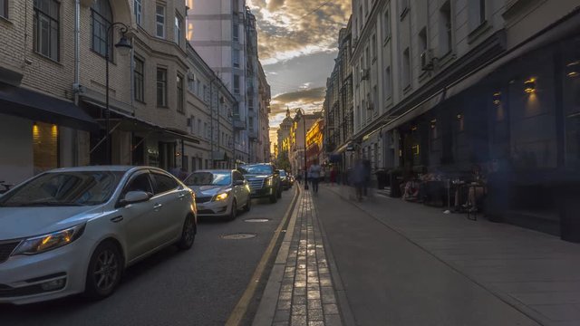 the flow of people and cars on a narrow street in the city center, time lapse