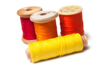 closeup of colorful sewing thread spool bobbins on white background