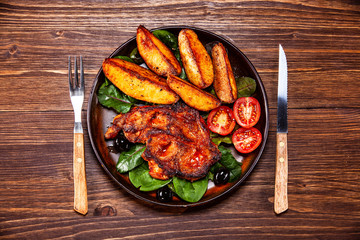 Grilled steak with potatoes and vegetables on wooden table