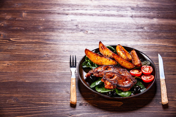 Grilled steak with potatoes and vegetables on wooden table