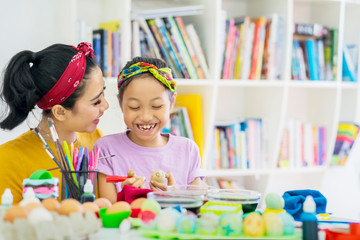 Fototapeta premium Happy little girl helped by her mother to dye eggs