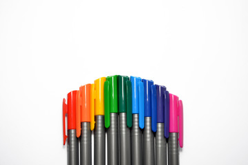 Set of rainbow pens, lying exactly in the form of an arc at the bottom side of the photo with copyspace