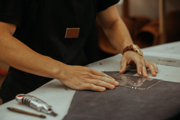 Close up of an artisan working with leather in his laboratory using tools. Handmade concept.