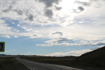 Naklejka premium road in steppe under a blue sky with white clouds Sayan mountains Siberia Russia