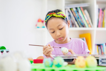 Little girl using a brush to paint Easter eggs