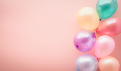 Party concept background, colorful balloons on pastel pink table, top view, copy space for text, selective focus