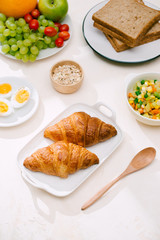 Healthy Breakfast served with milk, croissants, egg, cereals, oatmeal and fruits.