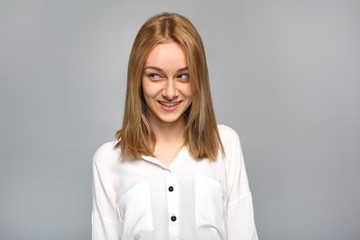 Young woman standing isolated on grey looking aside playful close-up