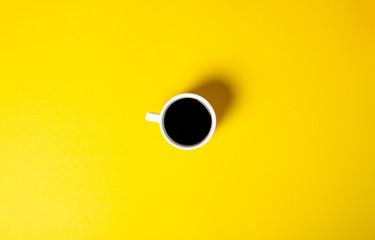 Cup of coffee drink on yellow background, top view