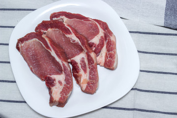 Raw meat steaks on a white plate