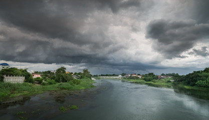 river view of dark clouds with heavy rain storm above Mae Klong river in Ban Pong District, Ratchaburi Province, west of Thailand.
