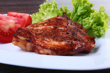 grilled pork chops with tomato, leaves lettuce and ketchup on plate.