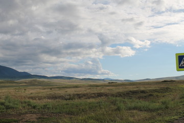 Wide steppe with yellow grass under a blue sky with white clouds Sayan mountains Siberia Russia