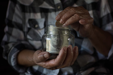 Old hand holding banknote in glass jar, protecting and saving money concept. color of retro style.