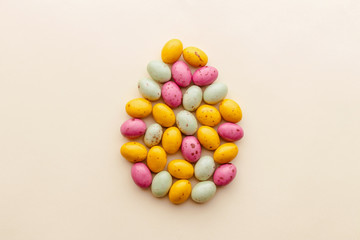Easter chocolate eggs candy on a pastel yellow background, creative flat lay easter concept, top view