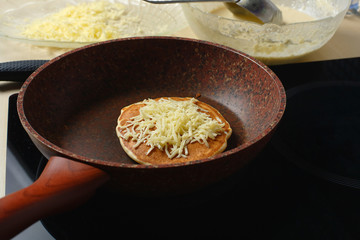 Baked without butter pancake in a pan sprinkled with grated cheese on top.
