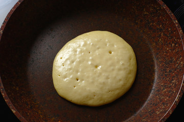 Baking pancake in a stone pan without oil. Close-up from above cooking.