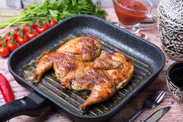 Fried chicken tobacco (tabaka) in a grill pan. Selective focus, close-up.