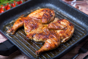 Fried chicken tobacco (tabaka) in a grill pan. Selective focus, close-up.
