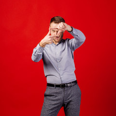 Man making a frame with his fingers over red background. people and emotion concept.