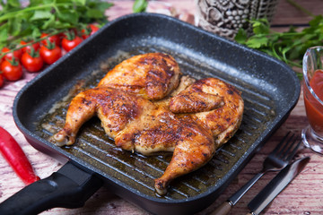 Fried chicken tobacco (tabaka) in a grill pan. Selective focus, close-up.