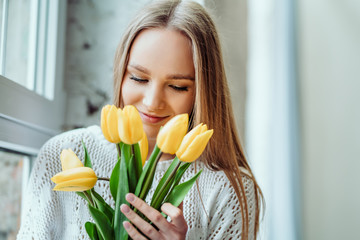 I love spring and flowers. Portrait of beautiful woman with bouquet of yellow tulips. Beauty and tenderness concept.