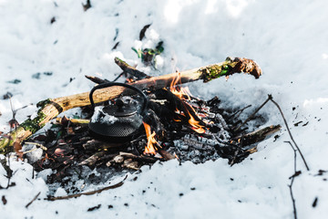 boiling kettle with steam on bonfire in winter forest