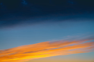 Amazing dramatic blue cloudy sky with orange sunshine in clouds. Atmospheric background in overcast...