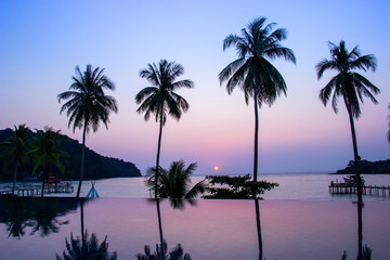 Fototapeta na wymiar Sunset reflecting on the water surface foreground with coconut trees area ao bang bao at Koh kood island is a district of Trat Province. Thailand.