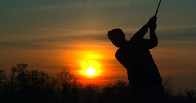 A Golfer chips a shot at sunset.