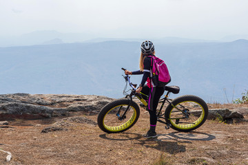 Female cyclist on mountain bike looking at mountain range view