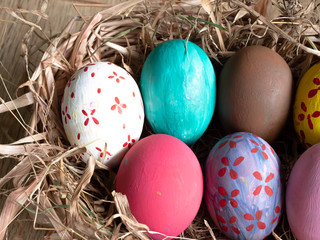 Colored eggs on a straw basket isolated on  wooden background.