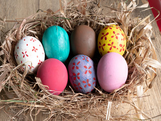 Colored eggs on a straw basket isolated on  wooden background.