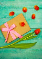 bouquet of red tulips on wooden background with envelope, tied with a ribbon space for text