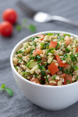 Oriental salad tabbouleh from bulgur, parsley and tomatoes in a white  bowl.